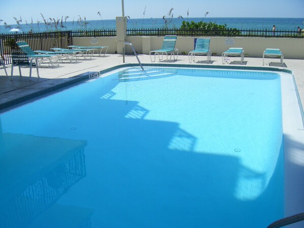 A swimming pool with lounge chairs and a view of the ocean.