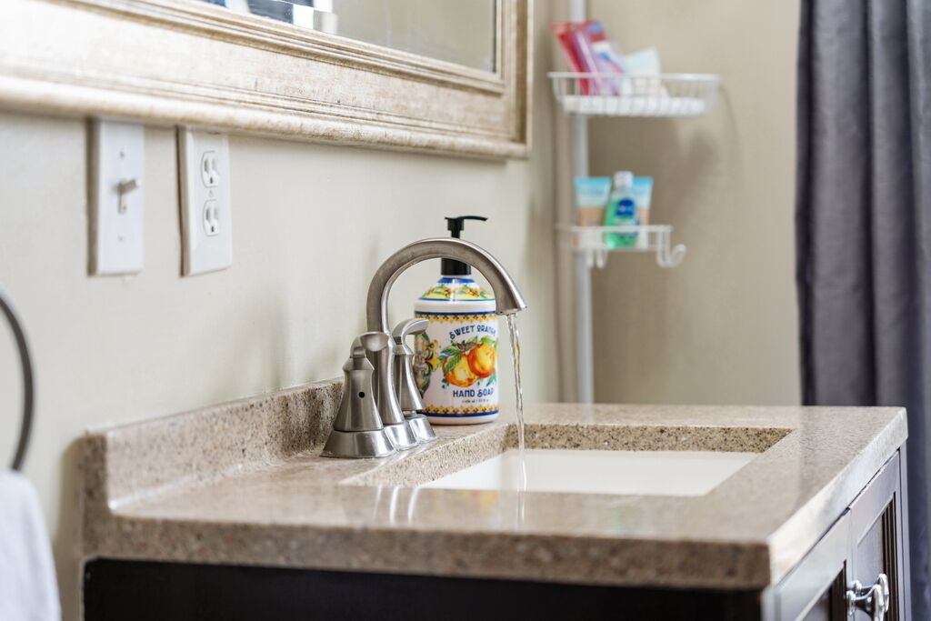 Une salle de bain avec un lavabo, un robinet et un distributeur de savon sur le comptoir.