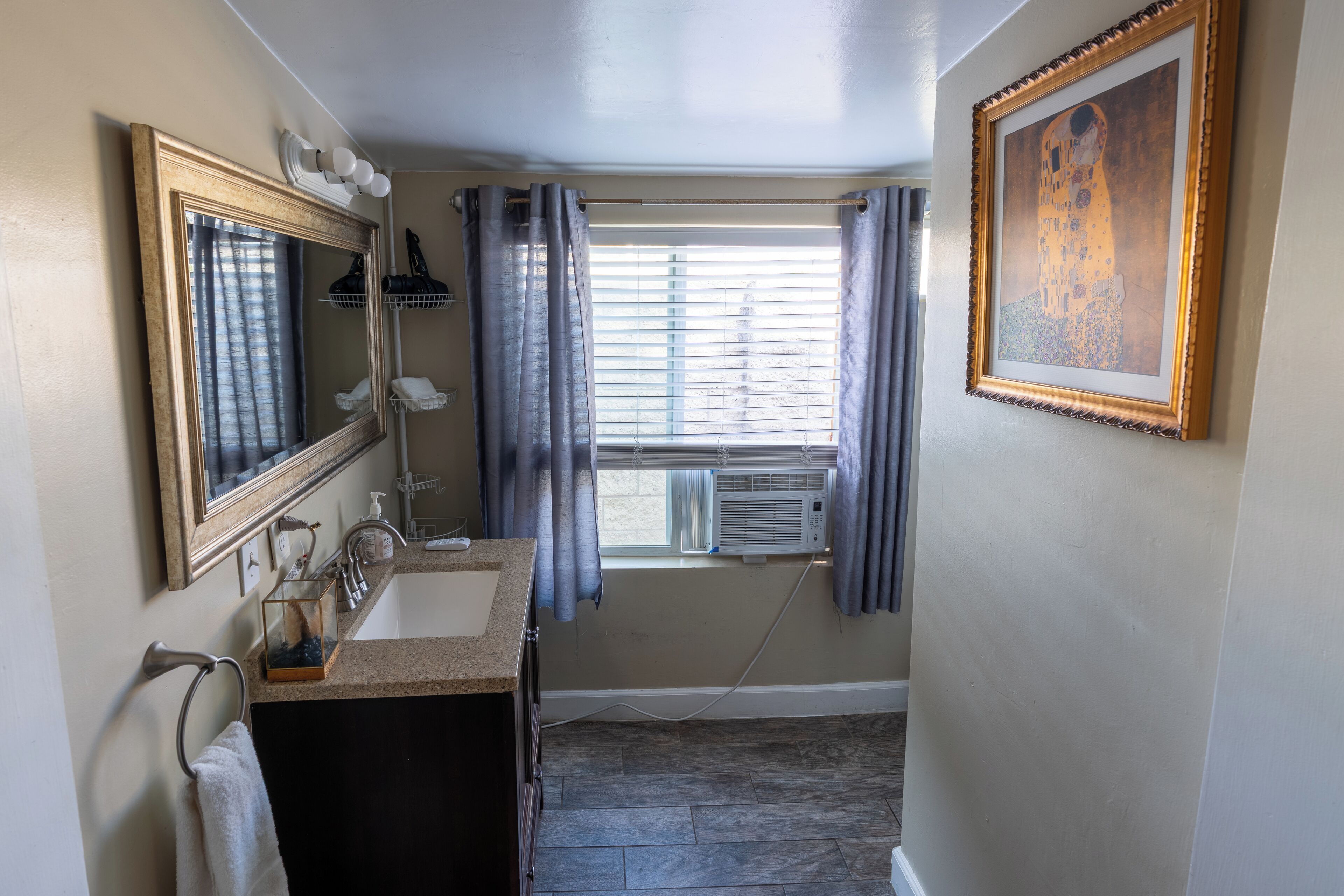 A bathroom with a sink, mirror, and window with curtains.