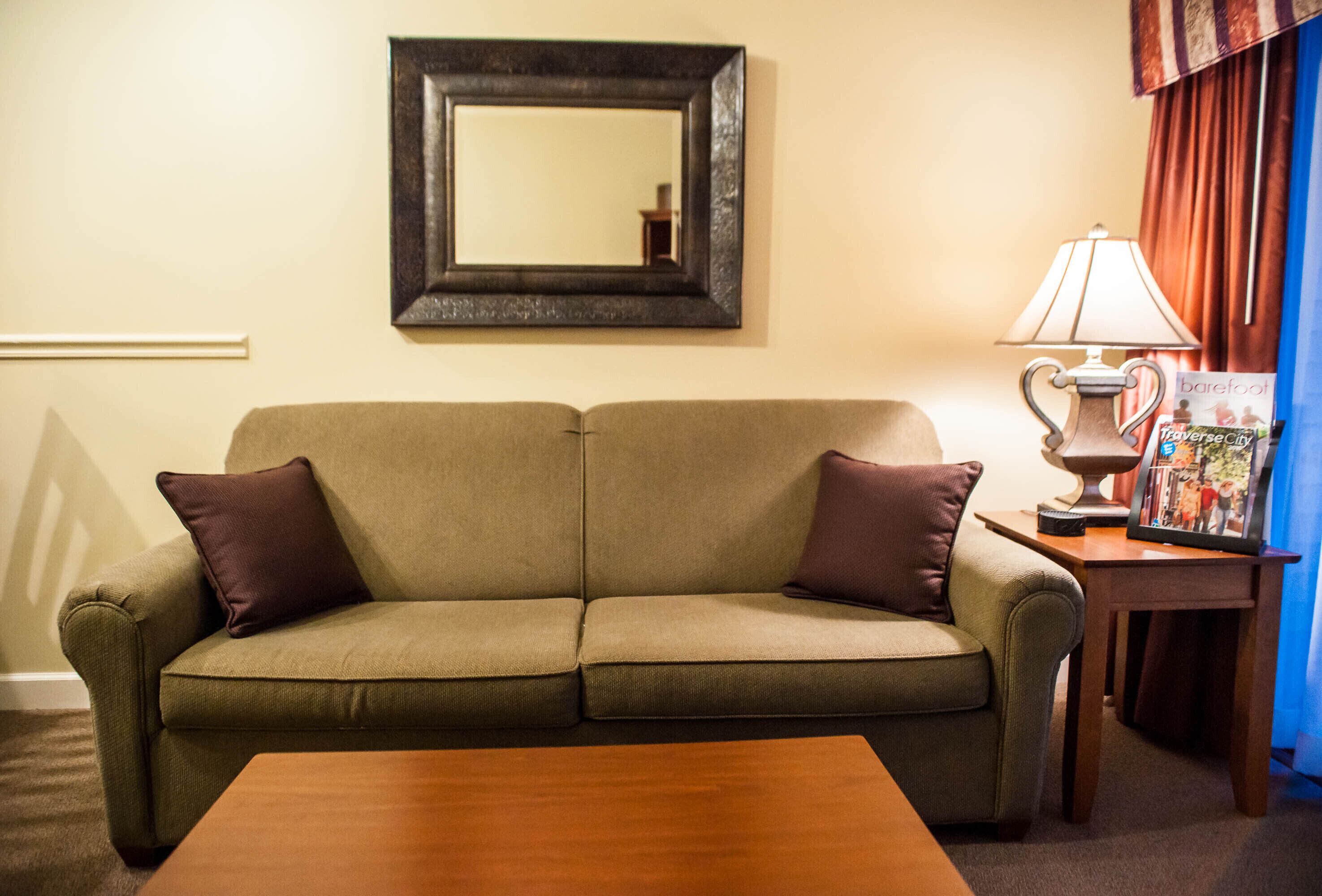A living room with a sofa, a coffee table, a lamp, and a framed picture on a side table.