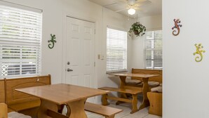 Une pièce avec une table et des bancs en bois, des murs blancs et un ventilateur au plafond.