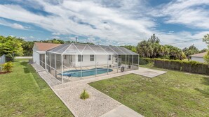 Une maison avec une piscine couverte et un jardin clôturé.
