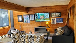 A cozy living room with a fireplace, patterned furniture, and wall-mounted artwork. - Seven Springs private spa, wifi, shuttle, air conditioner, pool (Champion)