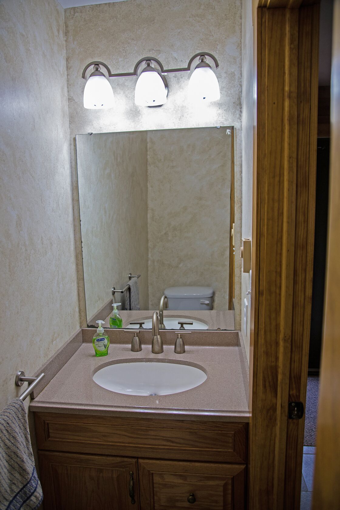 A bathroom with a sink, mirror, and three wall-mounted lights.