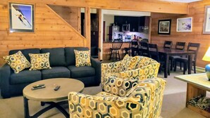 A cozy living room with a sofa, armchair, and coffee table. A staircase leads to a dining area with chairs and a table. - Seven Springs private spa, wifi, shuttle, air conditioner, pool (Champion)