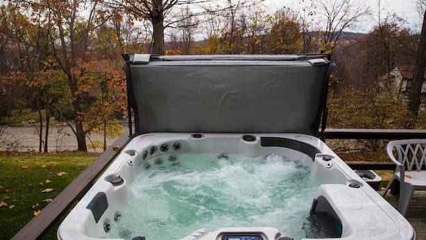 A hot tub with a control panel, surrounded by a wooden deck and trees in the background. - Seven Springs private spa, wifi, shuttle, air conditioner, pool (Champion)