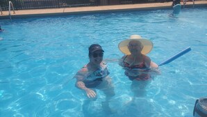 Two people in a swimming pool with a clear view of the pool's edge and a water bottle on the side. - Seven Springs private spa, wifi, shuttle, air conditioner, pool (Champion)