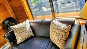 A wooden cabin interior with a black leather sofa and two decorative pillows with text. - Seven Springs private spa, wifi, shuttle, air conditioner, pool (Champion)