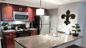 A modern kitchen with granite countertops, stainless steel appliances, and a central island with a bench. - Welcome To Potter's Castle! Near Disney, Slps 8, Harry Potter Decor, Pool, WOW! (Kissimmee)