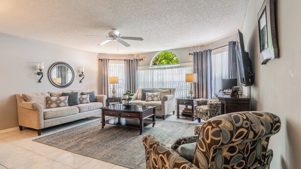 A living room with a sofa, armchair, coffee table, and a ceiling fan. - Welcome To Potter's Castle! Near Disney, Slps 8, Harry Potter Decor, Pool, WOW! (Kissimmee)