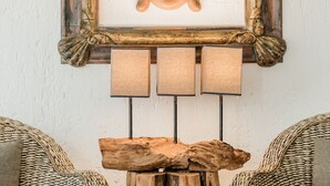 A room with two wicker chairs, a wooden table, and a Buddha head sculpture framed on the wall. - Luxurious & Comfortable Residence!!! - Hotel Zone - Condo on The Beach (Cancún)
