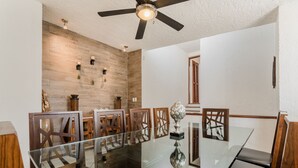 A dining area with a glass table, wooden chairs, and a ceiling fan. - Luxurious & Comfortable Residence!!! - Hotel Zone - Condo on The Beach (Cancún)