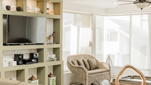 A living room with a large flat-screen TV, wicker furniture, and a ceiling fan. - Luxurious & Comfortable Residence!!! - Hotel Zone - Condo on The Beach (Cancún)