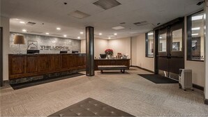 A reception area with a wooden reception desk, a wall-mounted sign, a bench, and a radiator. - A+ ski-in/out REMODEL NOW 2026 @ PC pool/gym/hot tub/washer/wifi/fireplace (Park City)