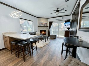 A modern kitchen with a fireplace, bar stools, and a dining area with a table and chairs.