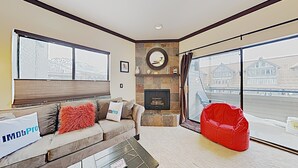 A living room with a fireplace, a large window, and a red bean bag. - A+ ski-in/out REMODEL NOW 2026 @ PC pool/gym/hot tub/washer/wifi/fireplace (Park City)