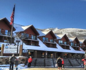 Un chalet comprenant plusieurs bâtiments, un télésiège et une montagne en arrière-plan.