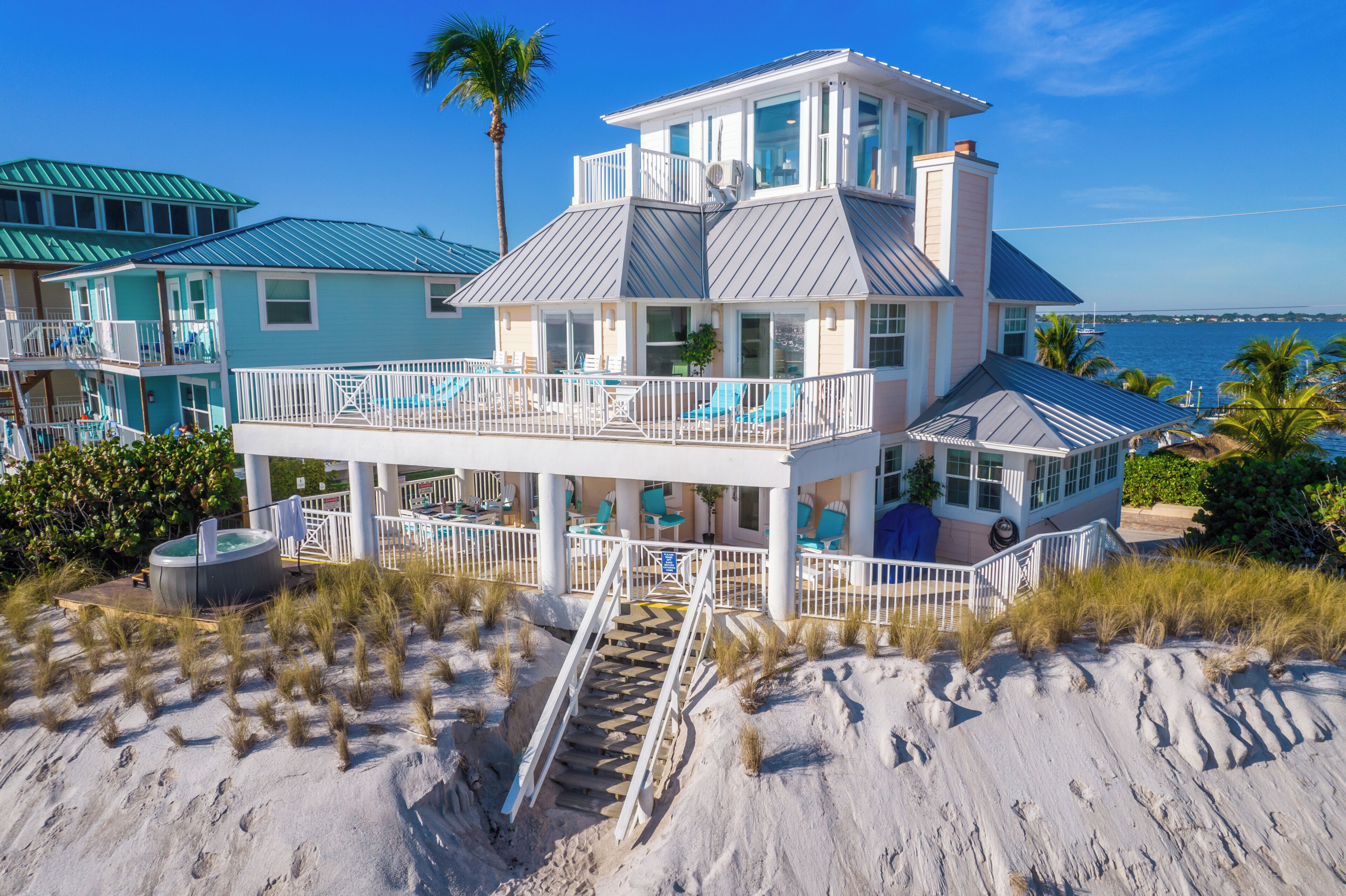A beachfront property with multiple levels, a pool, and a staircase leading to the beach.