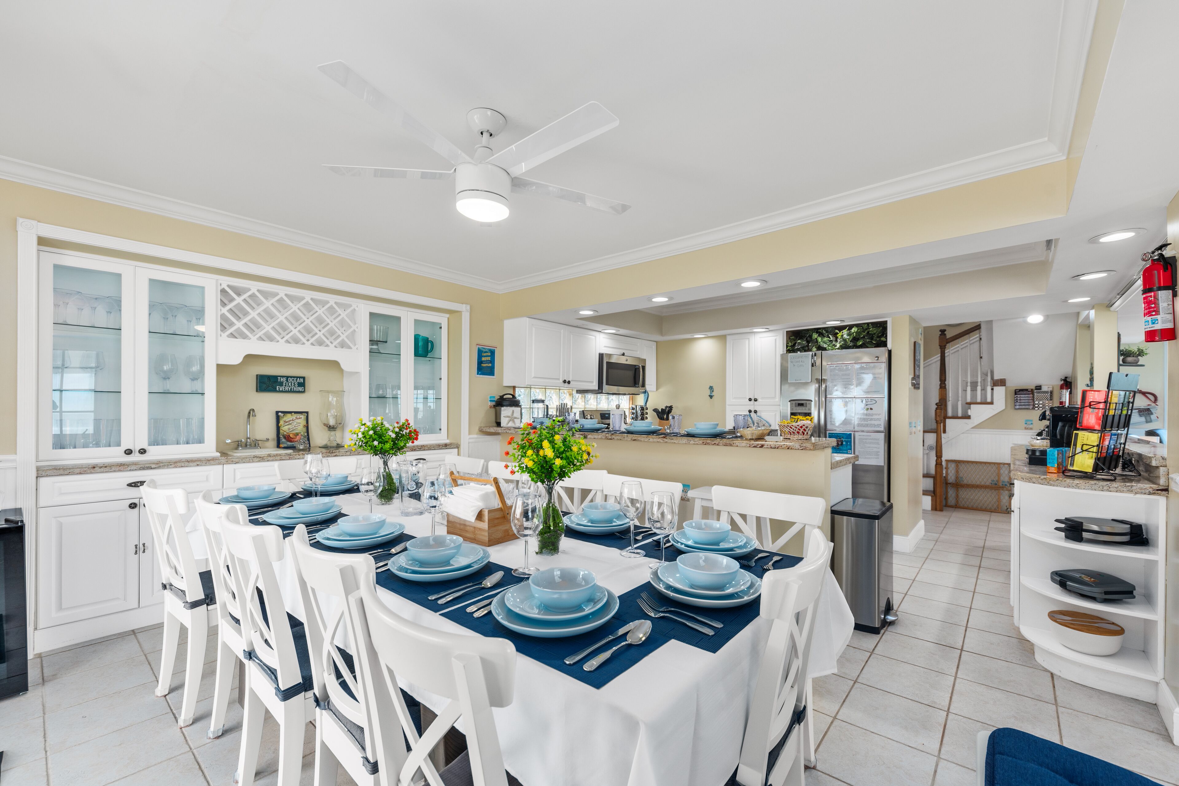 A spacious dining area with a high ceiling and a ceiling fan, a kitchen with modern appliances, and a view of the living area.