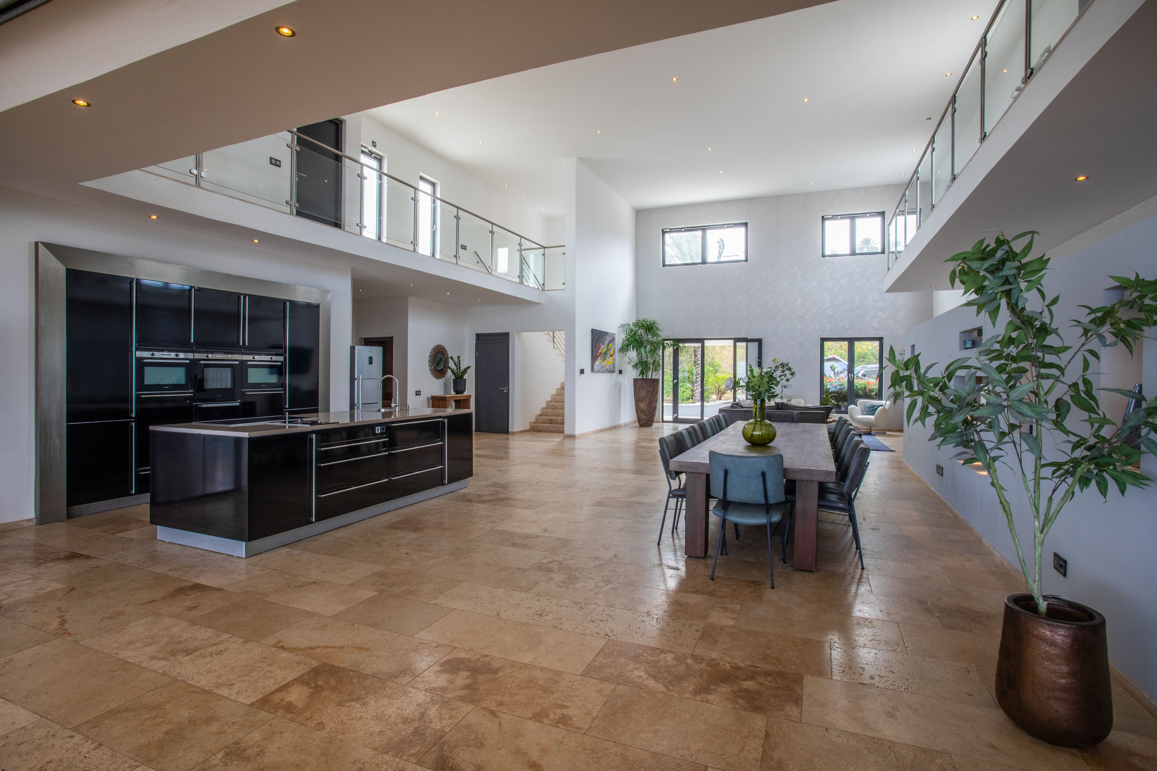 A spacious open-plan kitchen with a dining area, high ceilings, and a staircase to an upper level.