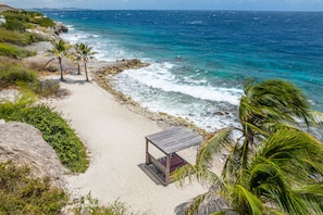 Een strand met een houten constructie, palmbomen en de oceaan.