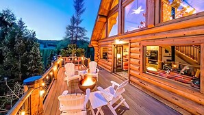 A wooden cabin with a deck, outdoor seating, and a fire pit.