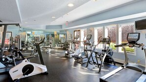 Un gimnasio con cintas de correr, elípticas y equipo de pesas.