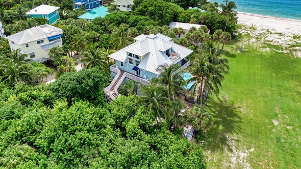 An aerial view of a coastal residential area with multiple houses surrounded by lush greenery and a beach. - ☀︎🏝⛱︎ Beachfront Elegance⛱︎🏝☀︎  
[2026 Spring + Summer Weeks Available Now!] (North Captiva)