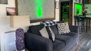 A living room with a black sofa, a crystal sculpture, and a green screen on the wall. - Art Studio: Historical Carriage House in the Poconos (Jim Thorpe)