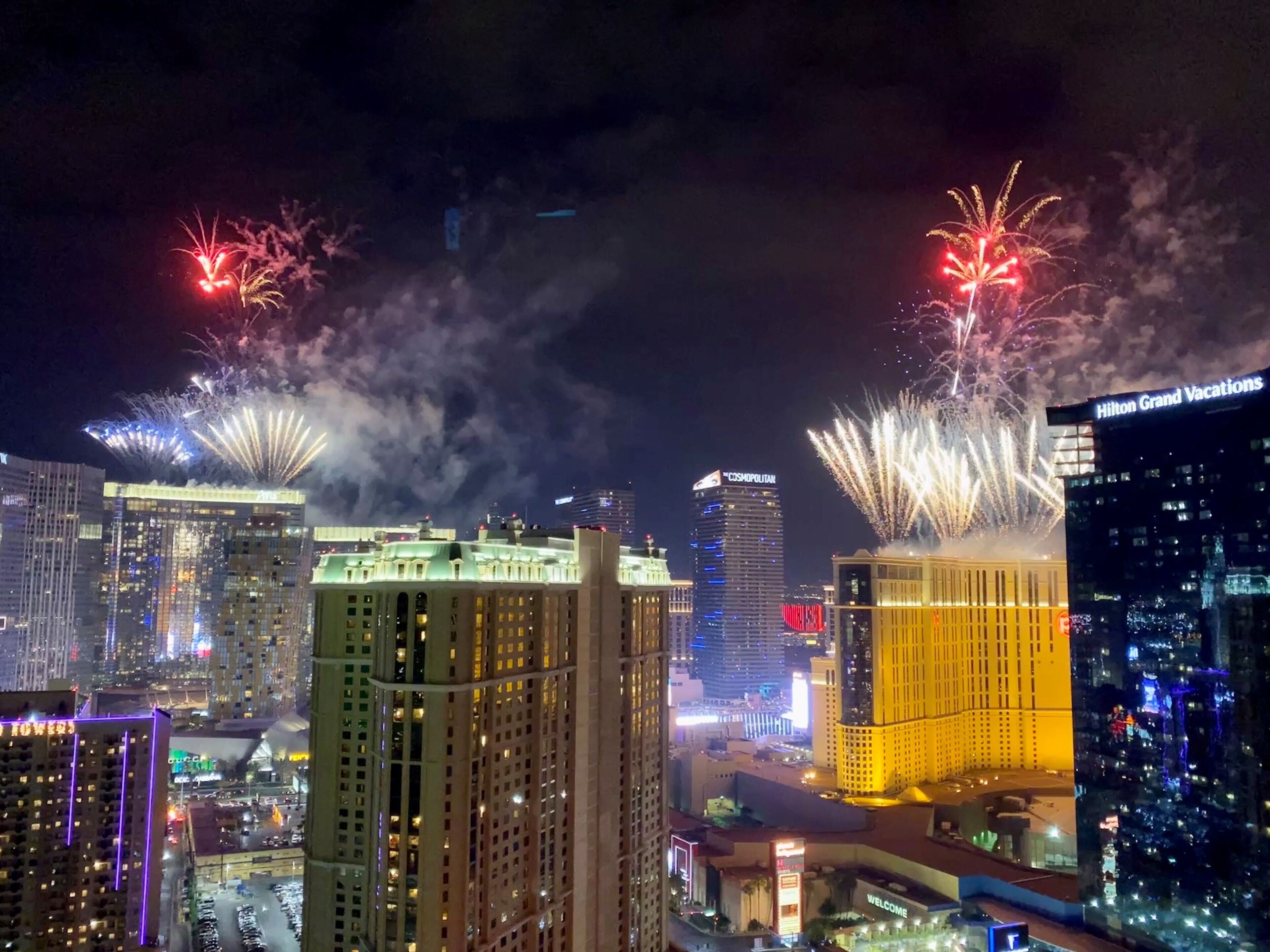 Une vue d'une ville avec des bâtiments illuminés et des feux d'artifice dans le ciel.