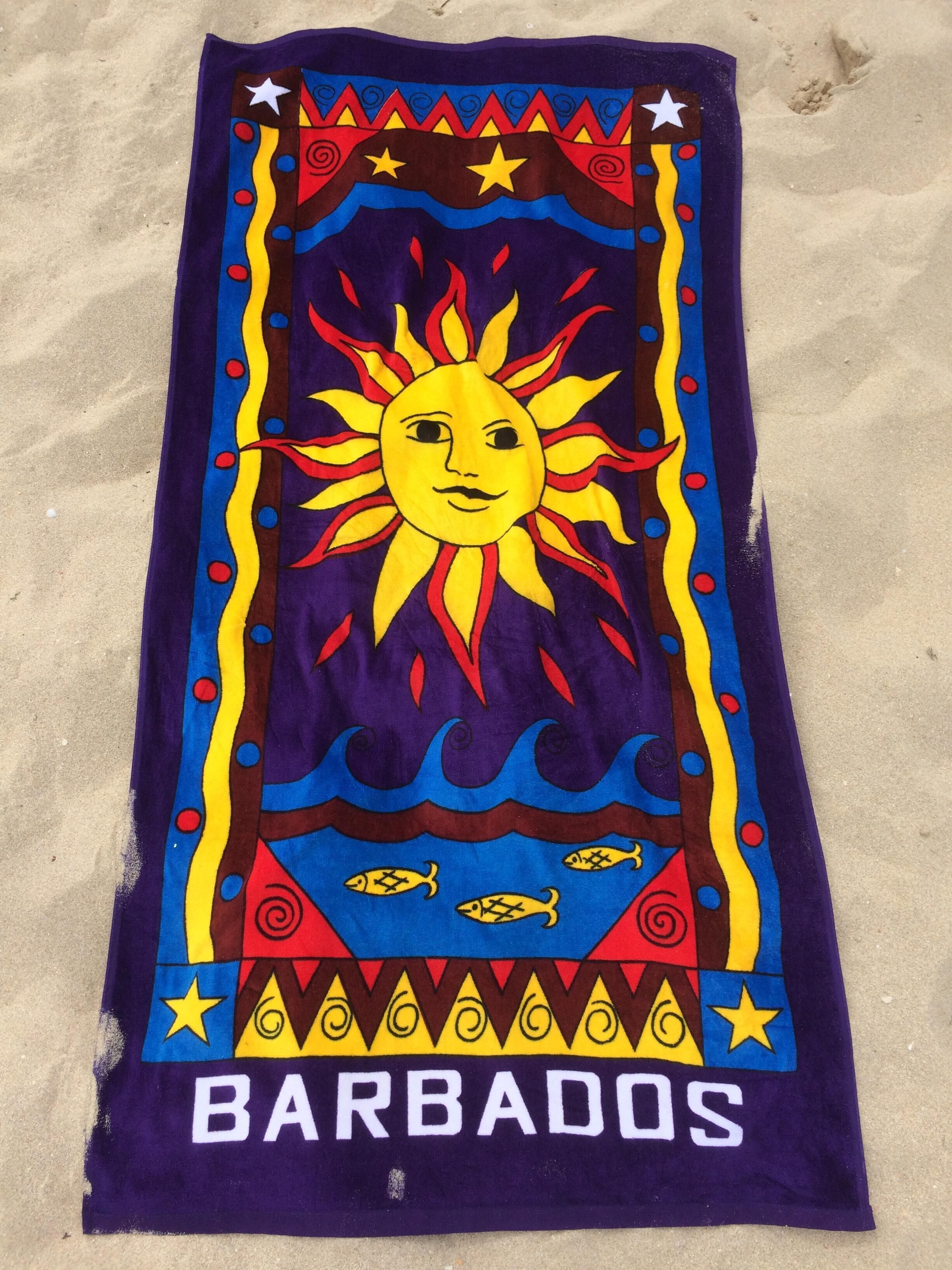 A towel with a sun and waves design, featuring the word "BARBADOS" at the bottom.