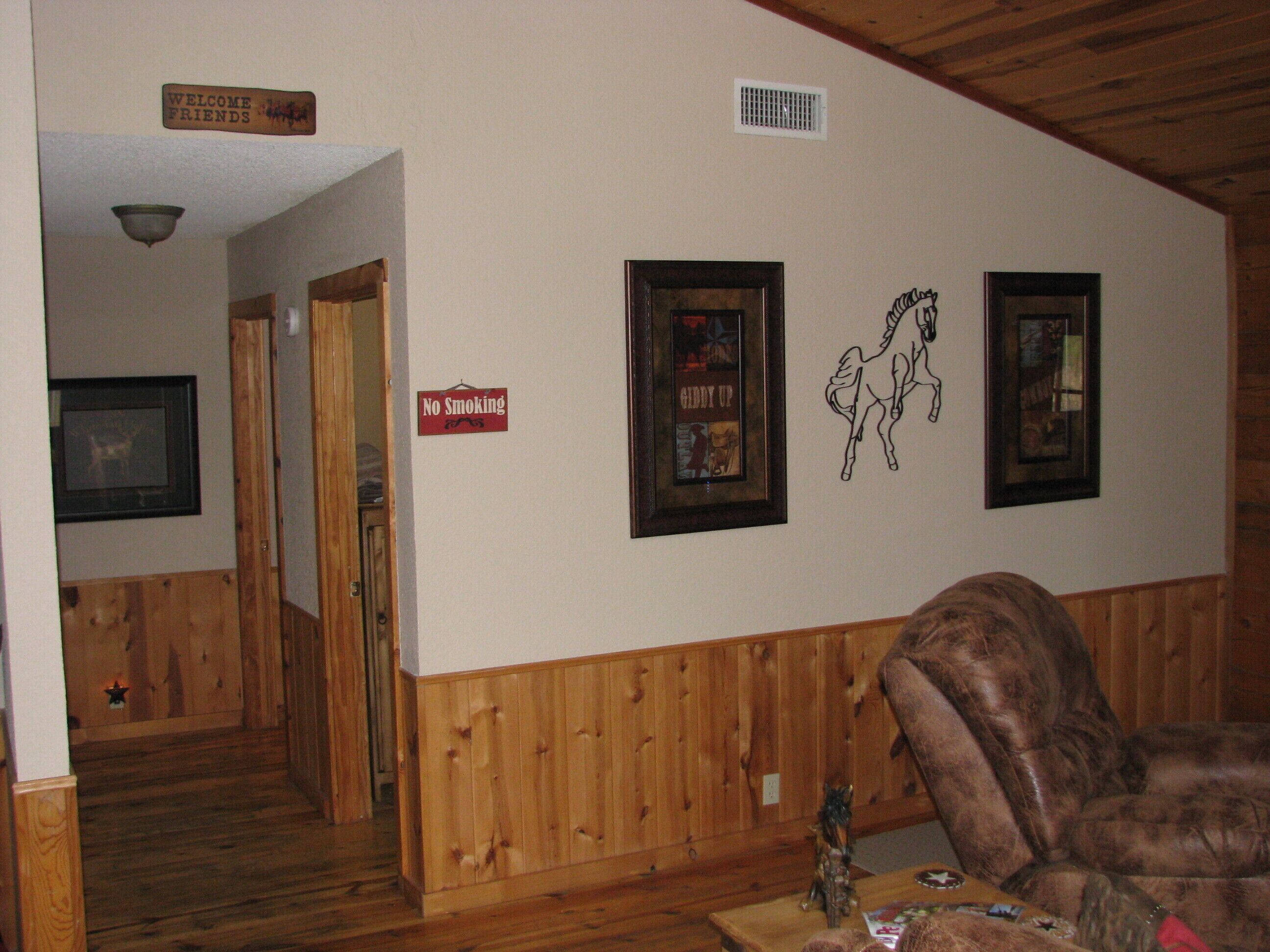 A wooden-paneled room with a 'No Smoking' sign, a 'Welcome Friends' sign, and framed pictures on the wall.