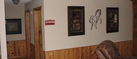 A wooden-paneled room with a 'No Smoking' sign, a 'Welcome Friends' sign, and framed pictures on the wall.