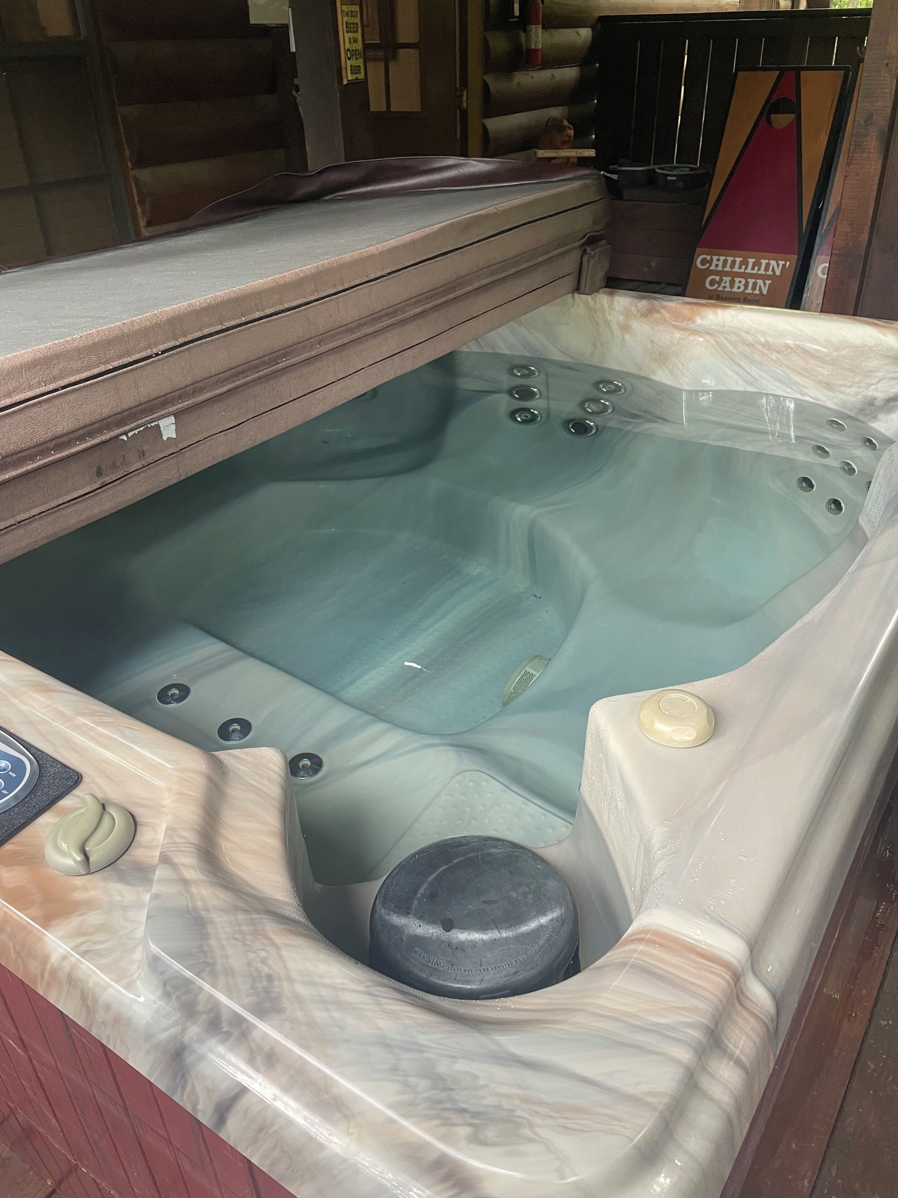 Un jacuzzi con panel de control, tapa de desagüe y un cartel que dice 'Chillin' Cabin'.
