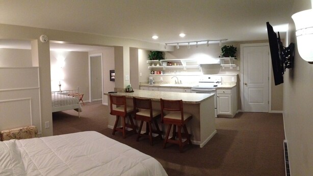 A bedroom with a large bed and a small sitting area with chairs.