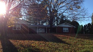 A house with a garage, surrounded by trees and a grassy yard.
