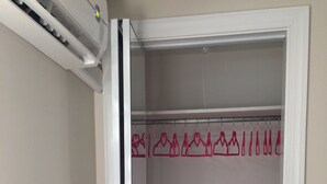 A walk-in closet with a wooden bench, a clothing rack with pink hangers, and a white door.