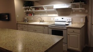 A kitchen with granite countertops, white cabinets, a built-in oven, and a stainless steel range hood.