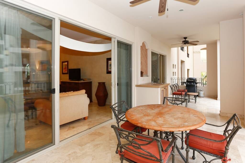 A spacious living area with a round table and chairs, a sofa, and a television.