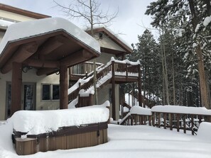 Eine Holztreppe führt zu einer überdachten Veranda mit Schneebedeckung.