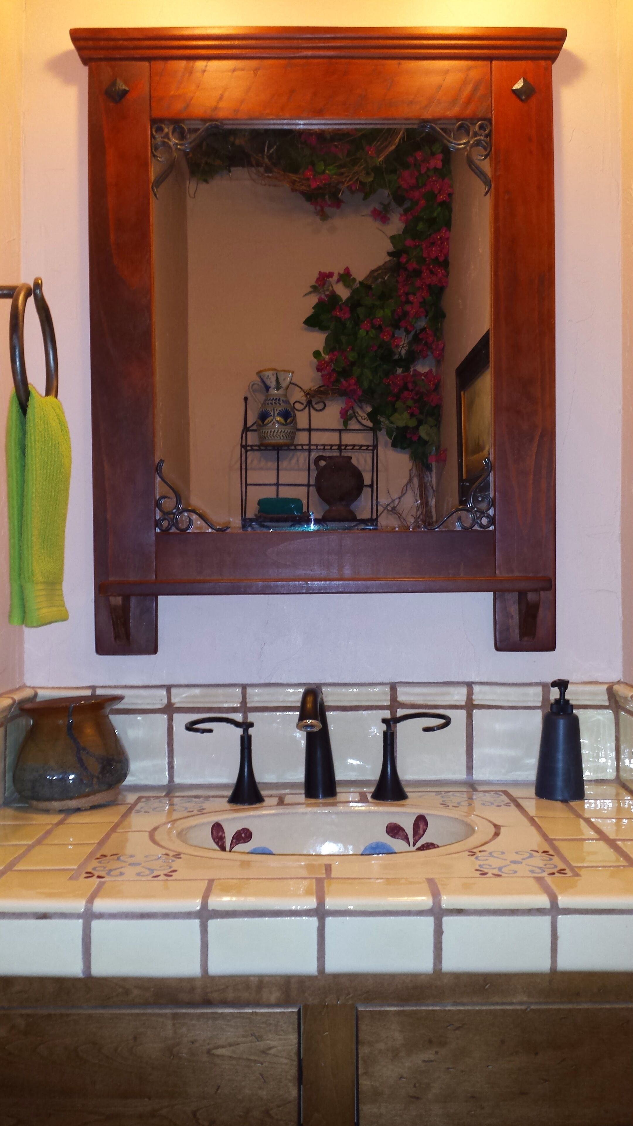 A bathroom with a wooden vanity, a mirror, a sink with three faucets, and a tiled backsplash.