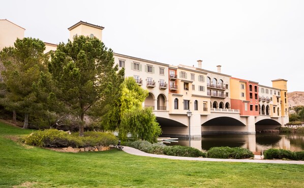 A multi-story building with balconies and a bridge over a body of water.