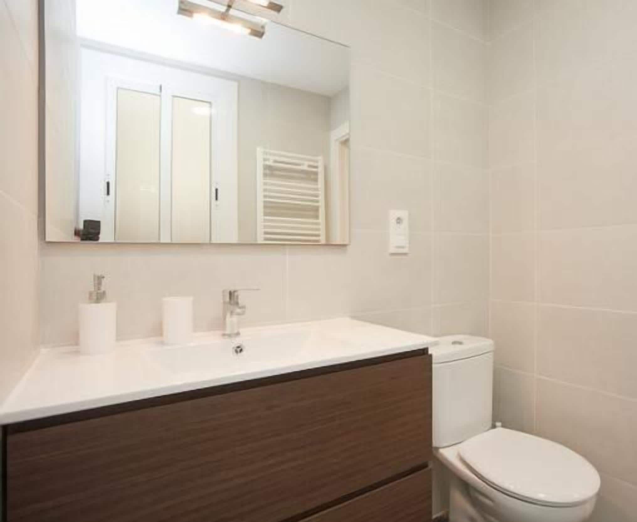 Ein modernes Badezimmer mit einem weißen Waschbecken, Spiegel und WC.