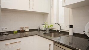 A modern kitchen with white cabinets, a granite countertop, a sink, a toaster, and a window. - Close Gaudi, Gracia equipped apartment, Barcelona, WIFI, balcony, AC & elevator (Barcelona)