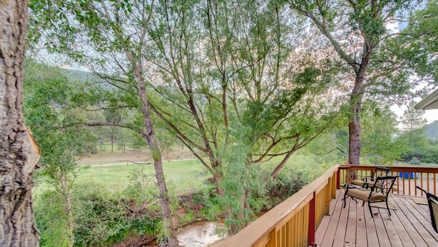Eine Holzterrasse mit Blick auf einen Bach und Bäume.