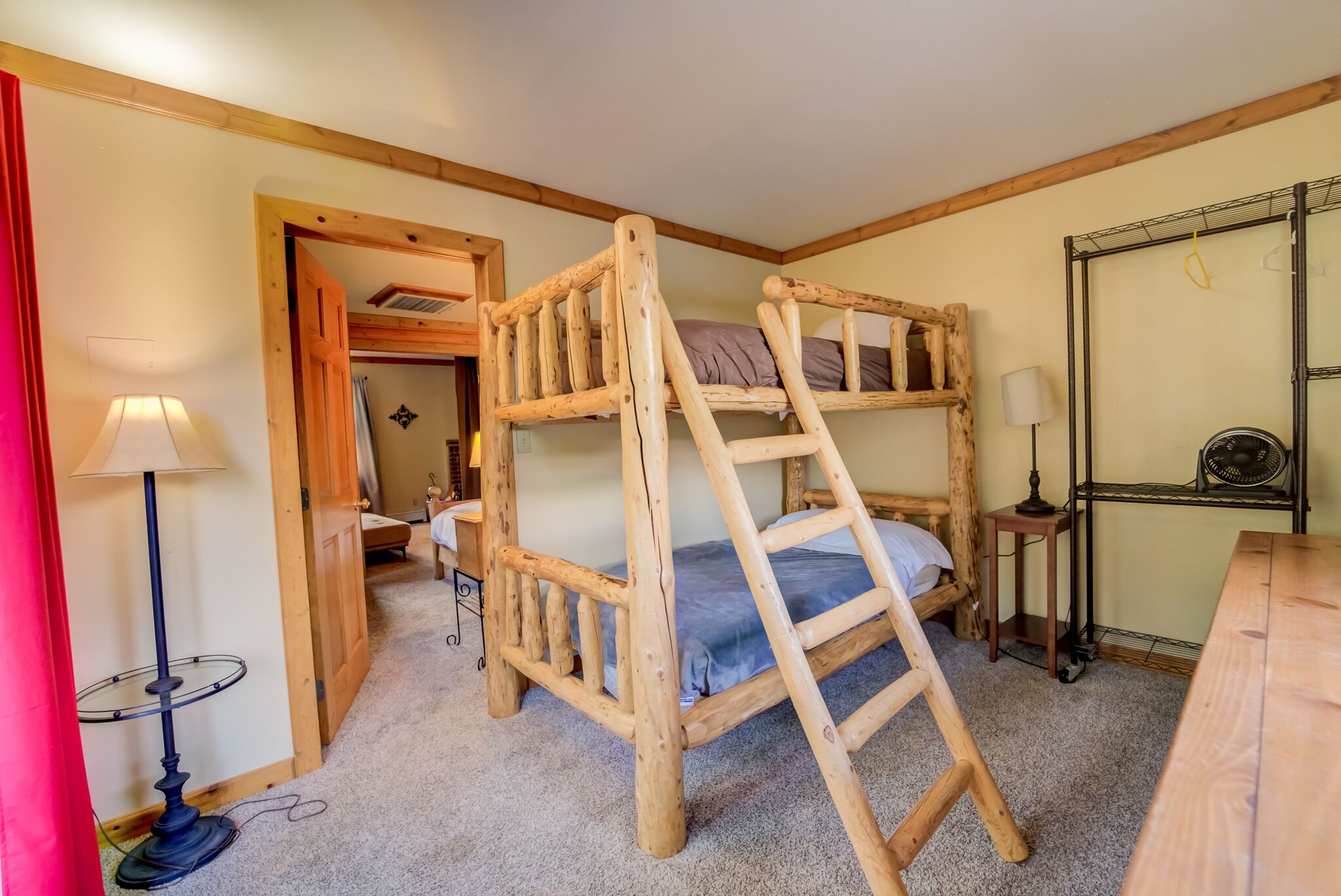 Une chambre avec un lit superposé, une échelle, un bureau, une lampe et un miroir.
