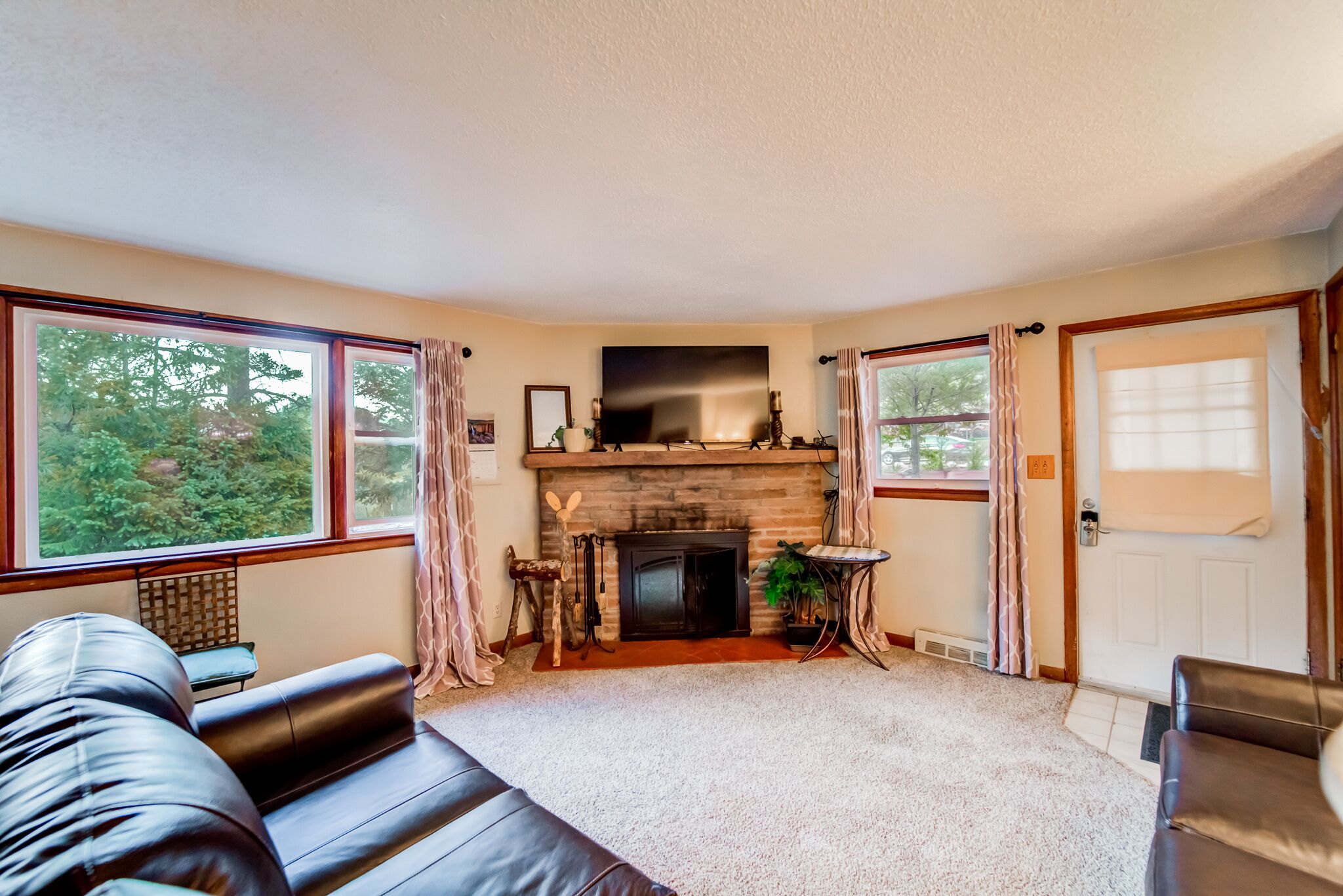 A cozy living room with a fireplace, large windows, and a comfortable leather sofa.