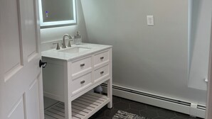 A bathroom with a white vanity, a large mirror, and a hexagonal tile floor.