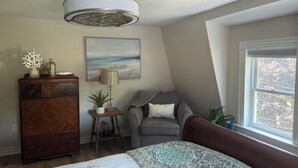 A bedroom with a bed, dresser, lamp, and a view of the outdoors through a window.