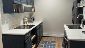 A modern kitchen with dark cabinets, a stainless steel refrigerator, a microwave, and a built-in oven.